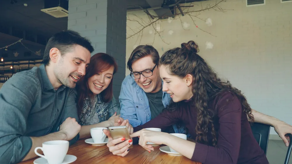 Friends looking at a phone together, guide to buy Instagram shares