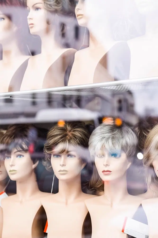 Rows of styled wigs on mannequin heads in a shop display, illustrating the wig styling niche on Instagram