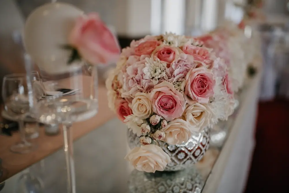 Elegant pink and white floral arrangement on a reception table, representing the editorial wedding design content style