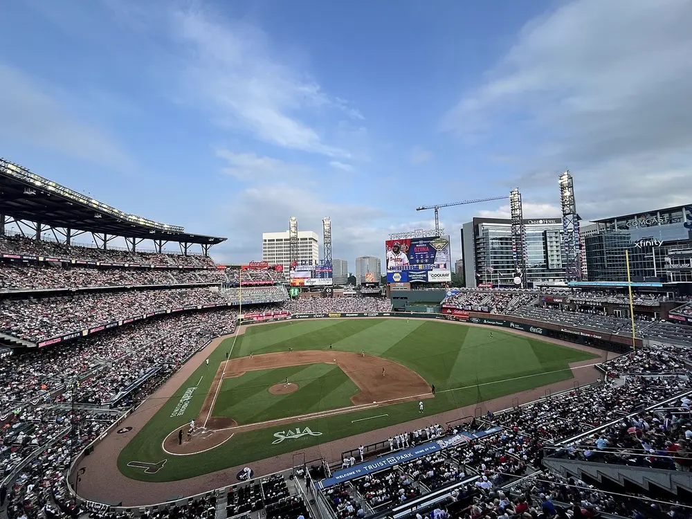 Wide view of Truist Park in Atlanta during a Braves home game, with full stands and the city skyline behind the scoreboard, illustrating professional baseball content on Instagram in the US