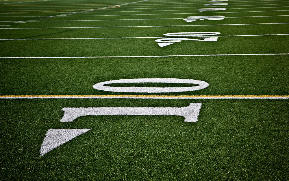 Yard line numbers painted on a green turf football field, illustrating college and NFL football content on Instagram in the US