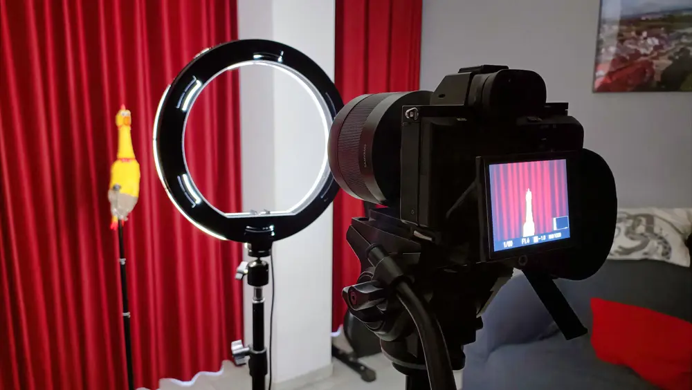 Camera on a tripod and a ring light set up in front of a red curtain, the kind of home studio behind comedy and vlog content on Instagram and YouTube in the US