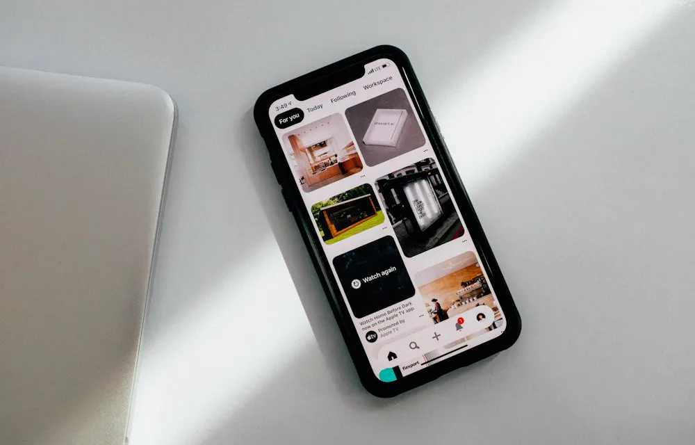 Phone showing a social media feed next to a laptop: how to choose a site to buy Instagram followers